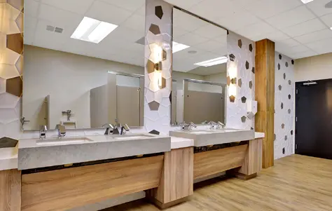 four sinks, grouped into two, with large mirrors per each group and small indented counter spaces buffering the sides of each group