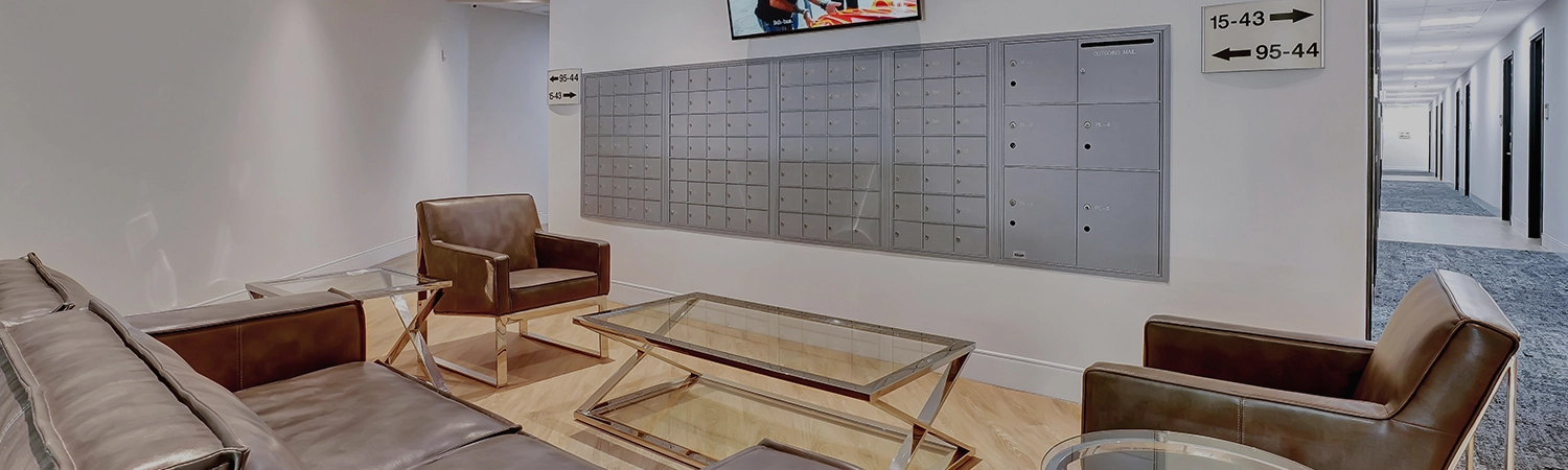 A wall of mailboxes with leather couches and glass coffee tables in the open area